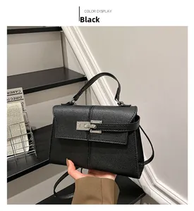 Detail of black lychee grain leather handbag with silver lock and long shoulder strap