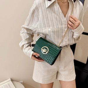 Dark green croc-effect crossbody bag with gold chain strap worn by a model