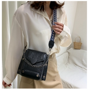 Detail of black leather crossbody bag with heart buckle and branded wide strap