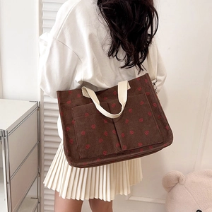Brown corduroy strawberry tote bag with off-white handles shown in a lifestyle setting