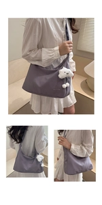 Close-up of a purple crossbody bag featuring a soft white cloud plush charm and text