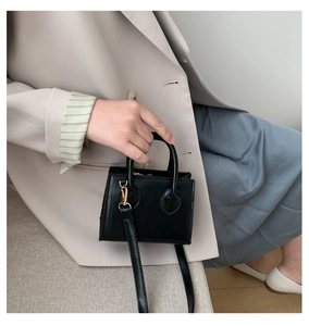 Close-up of black mini tote bag with gold hardware and adjustable shoulder strap
