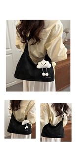 Detail of black canvas hobo bag with white lettering and a cute plush cloud charm