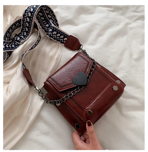 Detail of burgundy PU leather crossbody bag with heart buckle and ethnic shoulder strap