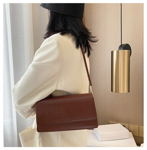 Brown crocodile pattern baguette bag with gold metal buckle shown on model's shoulder