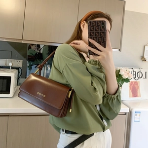 Deep brown leather flap shoulder bag with gold chain strap shown on model in mirror