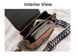 Detailed interior of brown pebbled leather shoulder bag with chain and geometric strap