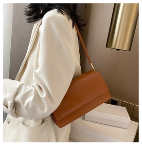 Detail of caramel crocodile pattern baguette bag with adjustable golden hardware