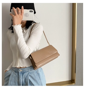 Detailed view of camel crocodile embossed baguette bag worn by a model over the shoulder