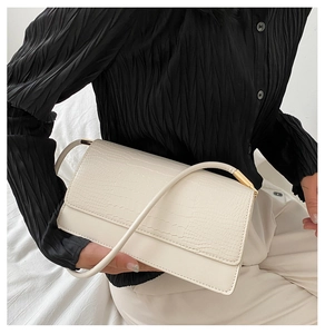 Detail of white crocodile-embossed underarm bag with gold metal hardware and sleek strap