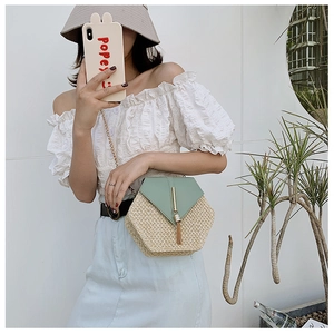 Detail of hexagon straw crossbody bag featuring mint green leather flap and gold tassel