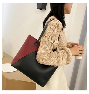 Detailed view of red and black color-block leather tote bag on model's shoulder