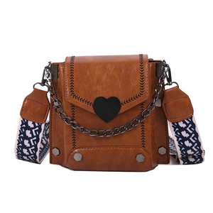 Brown faux leather crossbody bag with black heart buckle and woven geometric strap
