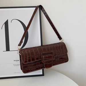 Detailed view of the dark brown crocodile pattern texture and large buckle on the baguette bag