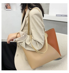 Close-up of beige and orange leather tote bag with long handles on a fashion model