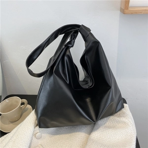 Detail of a black hobo bag with a knotted strap on a white wool coat background