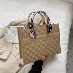 Détail du cabas matelassé beige avec lanière à logo et poignée en écharpe de soie