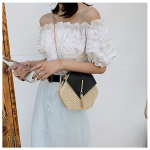 Close-up of hexagonal straw bag with leather flap, gold metal bar, and long tassel detail