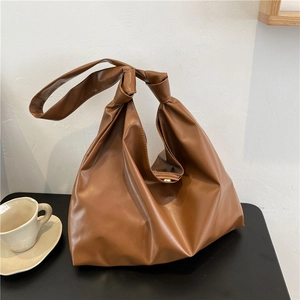 Detailed view of brown PU leather tote bag with stylish knot strap on the shoulder