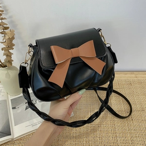 Détail du sac bandoulière avec grand nœud marron et bandoulière tissée noire chic
