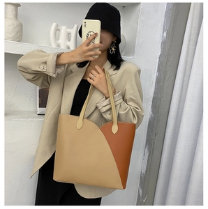 Fashionable beige and tan paneled tote bag shown styled on a model in a minimalist room