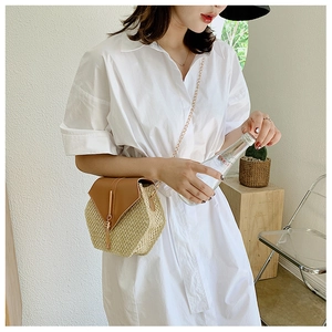 Detail of straw crossbody bag with leather flap and golden fringe on chain strap