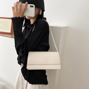 Chic cream crocodile pattern baguette underarm bag with gold hardware on black top model