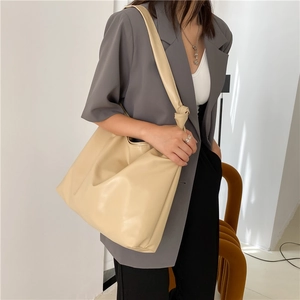 Detailed view of beige large capacity faux leather tote bag with knot shoulder strap