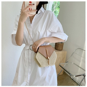 Detail of hexagonal straw crossbody bag with leather flap and gold tassel chain strap