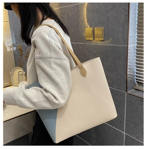Detail of minimalist cream and light blue contrast tote bag shown on a shoulder strap
