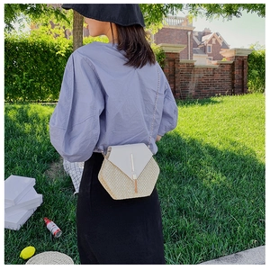 Outdoor shot of a woman wearing a hexagonal straw crossbody bag with gold chain strap