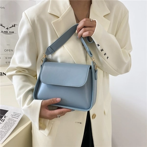 Close-up of light blue PU leather crossbody bag with wide shoulder strap and gold hardware