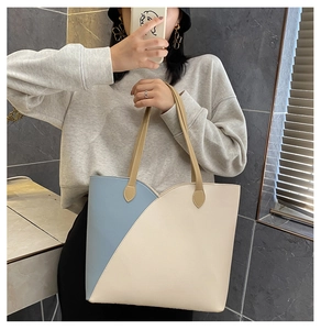 Detail of color-block tote bag featuring light blue and cream faux leather patchwork