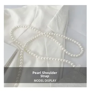 Detailed close-up of elegant white faux pearl shoulder strap on a white suit jacket