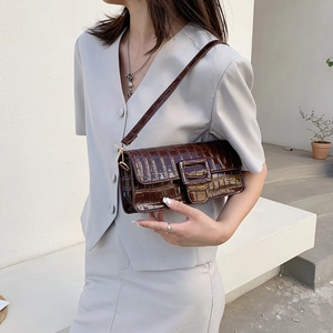 Deep brown crocodile embossed baguette shoulder bag shown on model in minimal grey suit