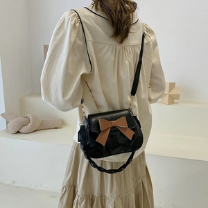 Détail du sac nuage noir avec nœud marron et poignée tressée porté par un mannequin