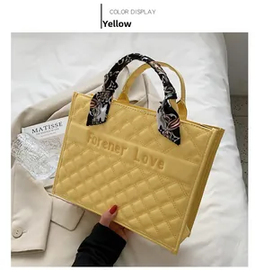 Détail du sac cabas matelassé jaune avec poignée en foulard et logo en relief