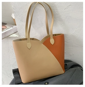 Detail of a large color-block tote bag with orange wavy stitching and slim shoulder straps