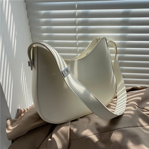 Detailed close-up of a minimalist cream shoulder bag featuring silver metal buckle and soft texture