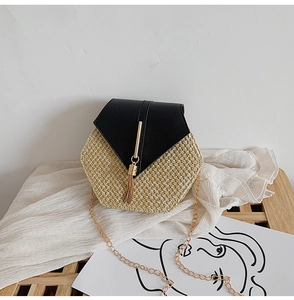 Detail of straw woven hexagonal crossbody bag with black leather flap and gold tassel
