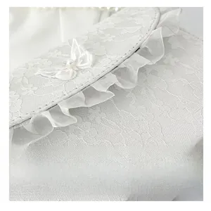 Detail of white lace crossbody bag with butterfly embroidery and pearl decoration