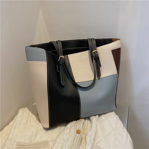 Détail de couture contrastée sur un sac cabas en similicuir à empiècements