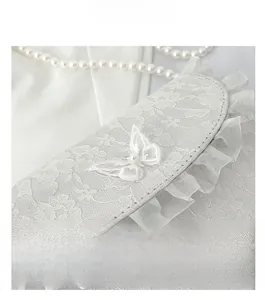 Macro detail of white floral lace crossbody bag with 3D butterfly and pearl accents