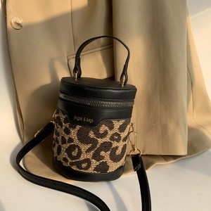 Detail of leopard print cylinder bag with gold hardware and black leather texture