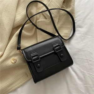 Vue de dessus d'un sac bandoulière noir en similicuir sur un pull en maille beige clair
