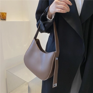 Detail of taupe crescent shoulder bag with wide strap and silver metal buckle