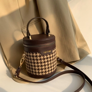 Macro view of retro cylinder handbag with brown houndstooth pattern and leather stitching