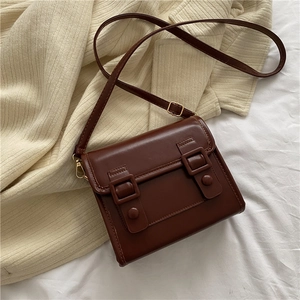 Détail d'un sac à bandoulière vintage marron foncé sur un fond en tricot beige douillet