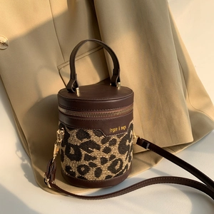 Detailed close-up of leopard print bucket bag with leather trim and gold hardware