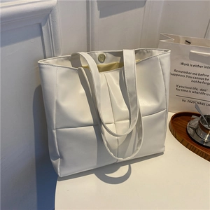 Close-up of cream white padded tote bag with quilted squares and magnetic gold buckle